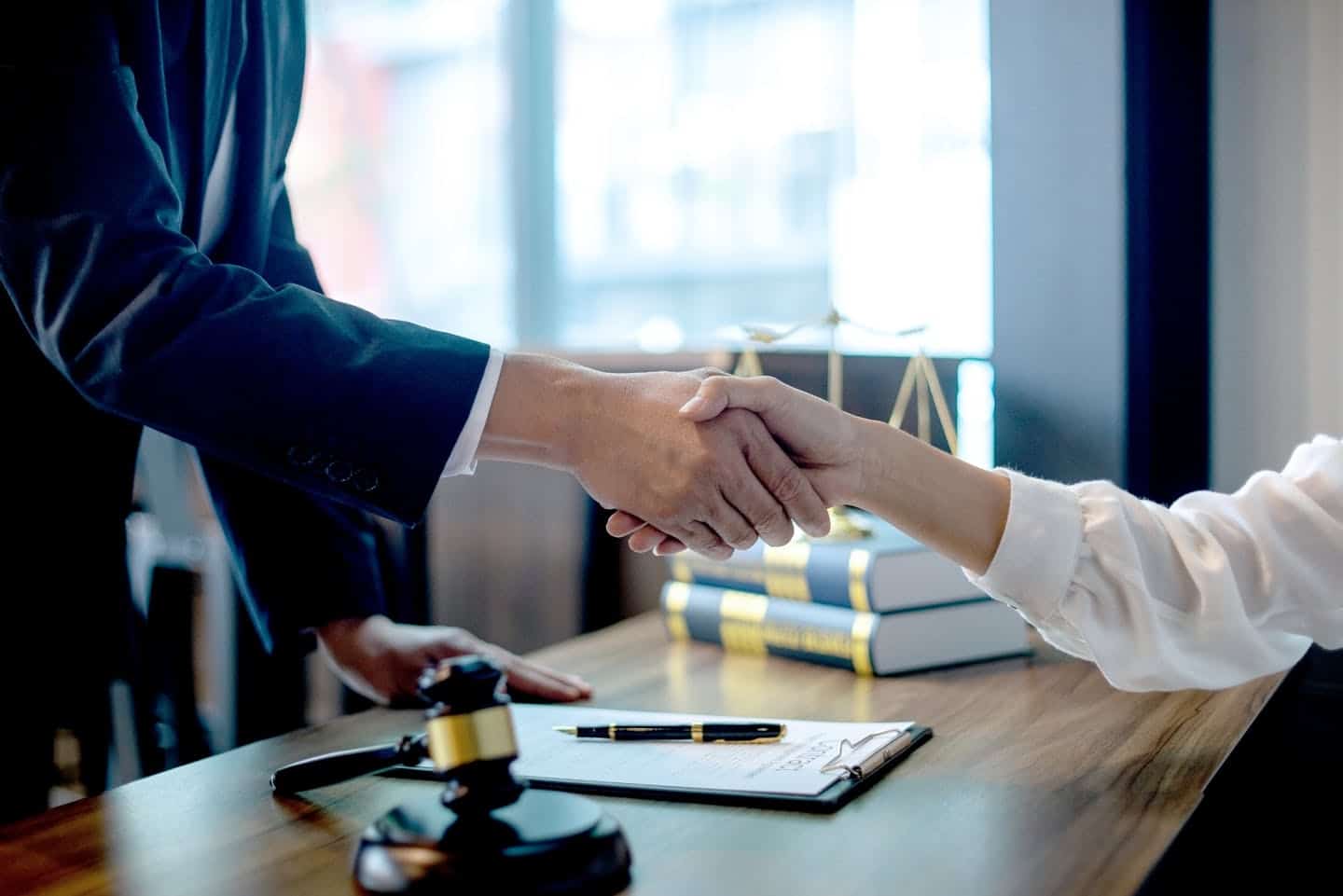 criminal defense lawyer shaking hands with a happy client over a desk