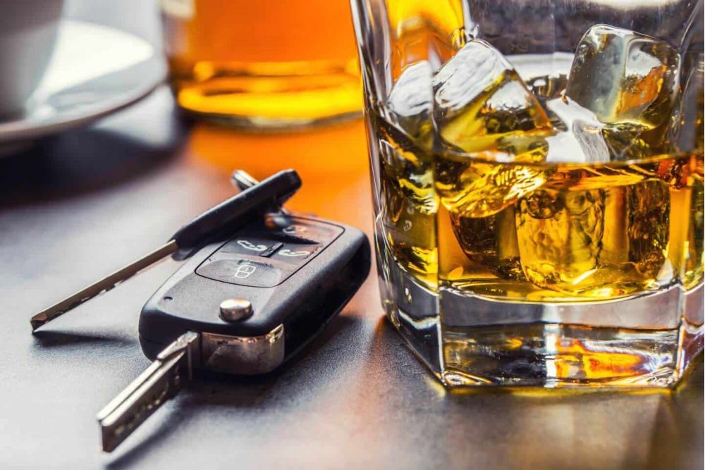 image of vehicle keys sitting next to a glass of alcohol representing the dangers of driving under the influence